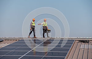 Engineers walking on roof inspect and check solar cell panel by hold equipment box and radio communication ,solar cell is smart gr