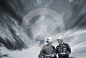 Engineers walking under dark clouds