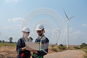 Engineers working and using a computer laptop on site in wind turbine farm