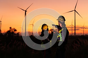 Engineers working on wind turbines farm at sunset,