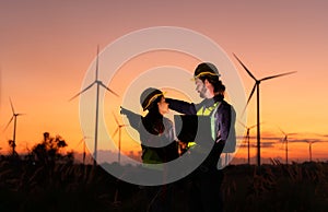 Engineers working on wind turbines farm at sunset,