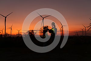 Engineers working on wind turbines farm at sunset,