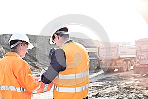 Engineers writing on clipboard at construction site against clear sky
