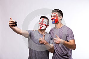 Futbaloví fanúšikovia Anglicko vs Slovensko si robia selfie fotografiu s telefónom na bielom pozadí.