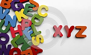 English Alphabet On A White Background. alphabets on a wooden surface. xyz - letters. scattered mixed colorful wooden letters of photo