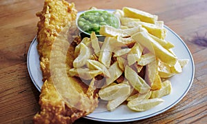 English battered Cod Fish and Chips with Mushy Peas in a plate