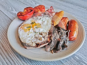 English Big Breakfast with sunny fried eggs, sausage, bacon, tomatos, hash brown, mushroom