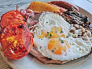 English Big Breakfast with sunny fried eggs, sausage, bacon, tomatos, hash brown, mushroom