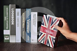 English book is selected from the bookshelf for English language learning.