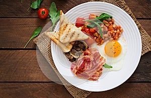 English breakfast - fried egg, beans, tomatoes, mushrooms, bacon and toast.