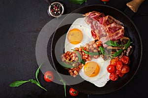 English breakfast - fried egg, beans, tomatoes, mushrooms, bacon and toast.