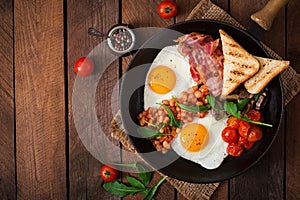 English breakfast - fried egg, beans, tomatoes, mushrooms, bacon and toast.