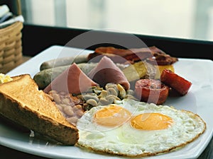 English breakfast with fried eggs, sausages, bacon, beans and toast