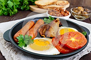 English breakfast: sausages, bacon, tomatoes, egg, beans in sauce, fried mushrooms, toast