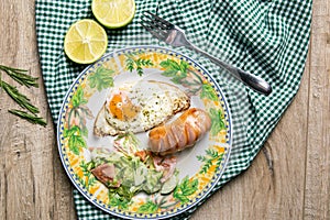 English breakfast, scrambled eggs with sausage and cabbage salad, next to it is a lime cut in half, a plate stands on a wooden