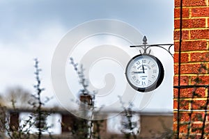 English brick house corner with dangling retro clock with Paddington Station London text on it