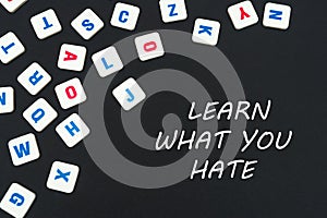 English colored square letters scattered on black background with text learn what you hate