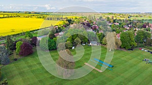 English cricket pitch with colorful trees in a village in the English countryside