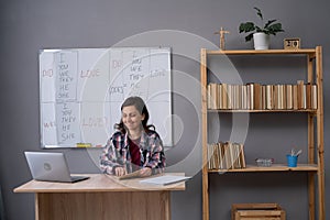 English female teacher having video conference chat with students, talking to laptop web camera, explaining grammar