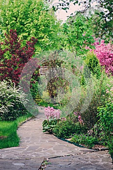 English garden in spring. Beautiful view with blooming trees and shrubs.