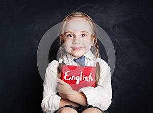 English language concept. Cute child pupil with book smiling