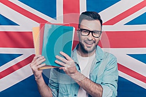 English language learning concept-portrait of cheerful attractive man with bristle showing colorful copy books standing over Engli