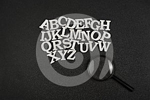 English letters in alphabetical order from A to Z on black background. next to magnifying glass