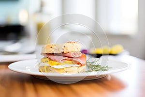 english muffin egg sandwich with ham and melted cheese on a plate