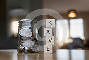 English pound string coin and pennies nickels in jar with SAVE on wooden stack with blurry background Financial planing for 2022