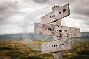 English, spanish and french wooden signpost outdoors.