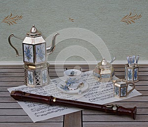 English tea set and a block flute on a sheet of music