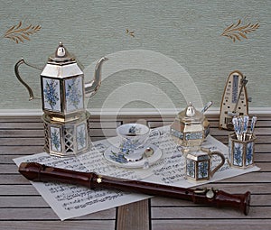 English tea set, metronome for music and a block flute on a sheet of music