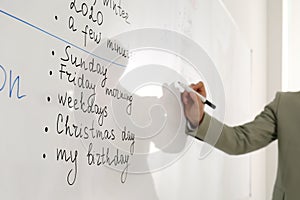 English teacher giving lesson in classroom, closeup. Focus on whiteboard