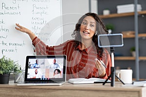 English teacher pointing on board, explaining lesson to diverse students