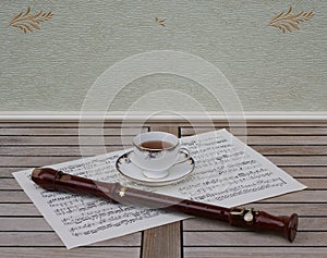 English teacup with saucer, fine bone china porcelain, and a block flute on a sheet of music