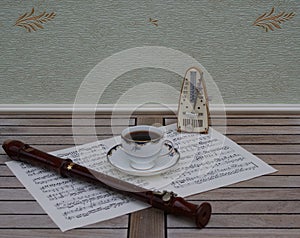 English teacup with saucer, fine bone china porcelain, metronome for music and a block flute on a sheet of music