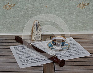 English teacup with saucer, fine bone china porcelain, metronome for music and a block flute on a sheet of music