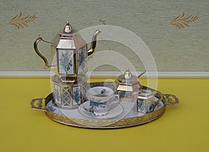 English teacup, saucer, silver-plated teapot on a silver stove, cream jug, sugar bowl and sugar spoon on a tray