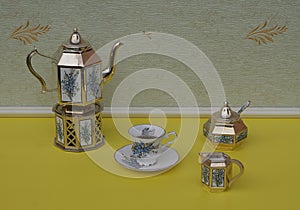 English teacup, saucer, silver-plated teapot on a silver stove, cream jug, sugar bowl and sugarspoon, with floral decor