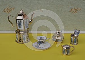 English teacup, saucer, silver-plated teapot on a silver stove, spoon vase and teaspoon, cream jug, sugar bowl and sugarspoon