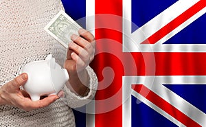English woman with money bank on the background of UK flag. Dotations, pension fund, poverty, wealth, retirement concept