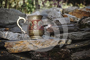 Engraved metal brass mug standing on stones