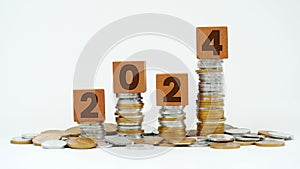 Engraved year 2024 on wooden cube on top of pile of coins