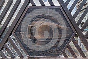 Engraving on metal representing the Super Hitachi train on the Shimogoindenbashi Bridge that reaches the Nippori and Yanaka