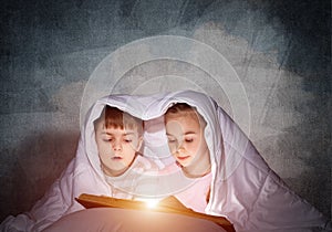 Engrossed little girl and boy reading book