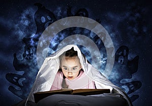 Engrossed little girl reading book in bed