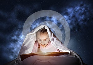 Engrossed little girl reading book in bed