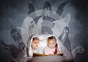 Engrossed little kids reading book in bed