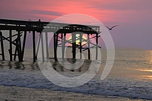 An enhance sunrise shines through the beach fishing pier on Amelia Island