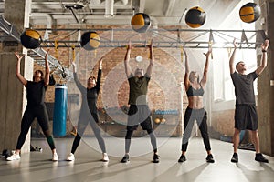 Enhance your Health. Full length shot of sportive people in black sportswear using exercise ball while having workout at